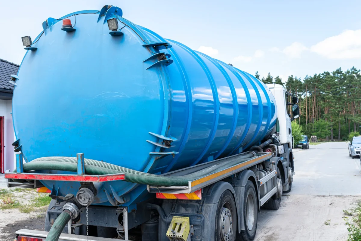 Large blue vacuum tanker with a connected suction hose