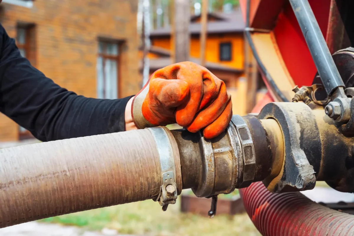 Gloved operative connecting a reinforced suction hose to a drainage tanker