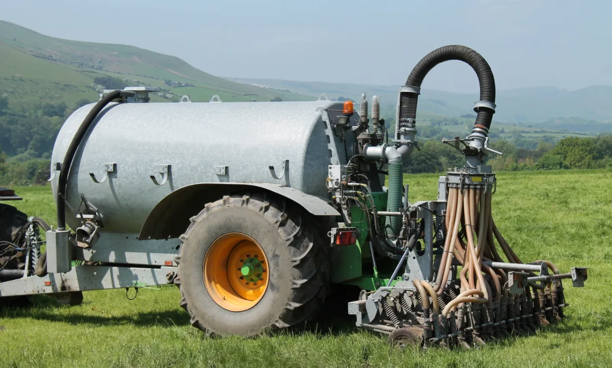 Agricultural slurry tanker and tractor working across a field
